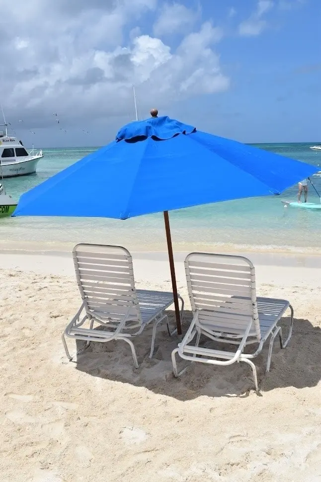 Aruba umbrella and two reclining chairs waiting on the sand at Palm Beach